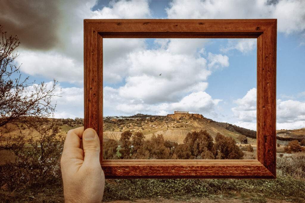 Una cornice di legno tenuta davanti al paesaggio di Agrigento